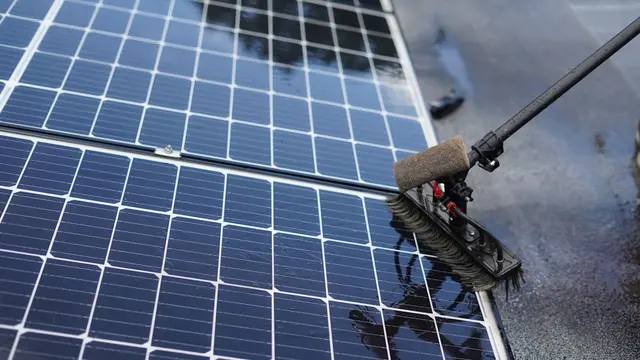Cleaning solar panels with a long handled brush.