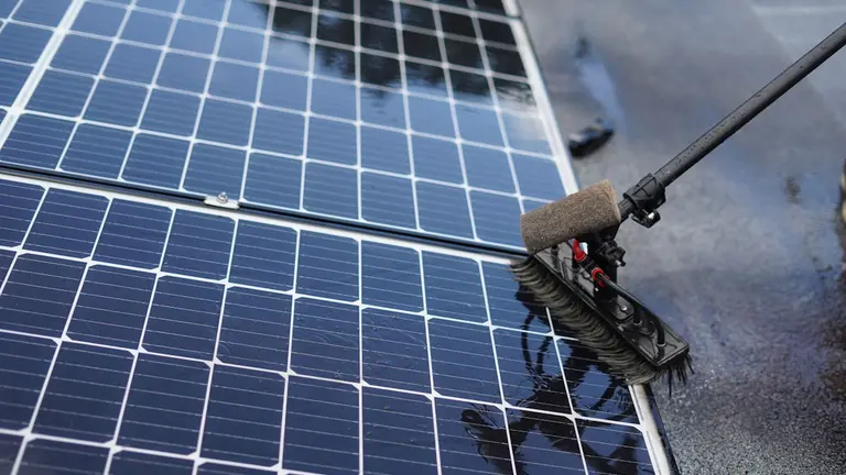 Cleaning solar panels with a long handled brush.